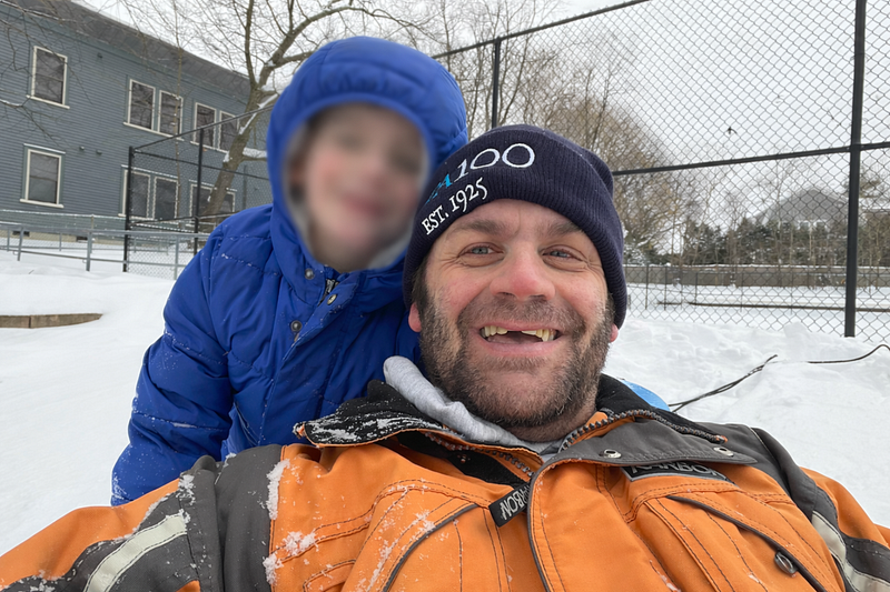 David Cutler and his son outdoors in snow; the child’s face is blurred in the original photograph.